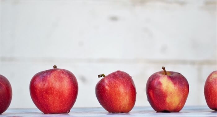 Vier knackige rote Äpfel nebeneinander auf einem Tisch